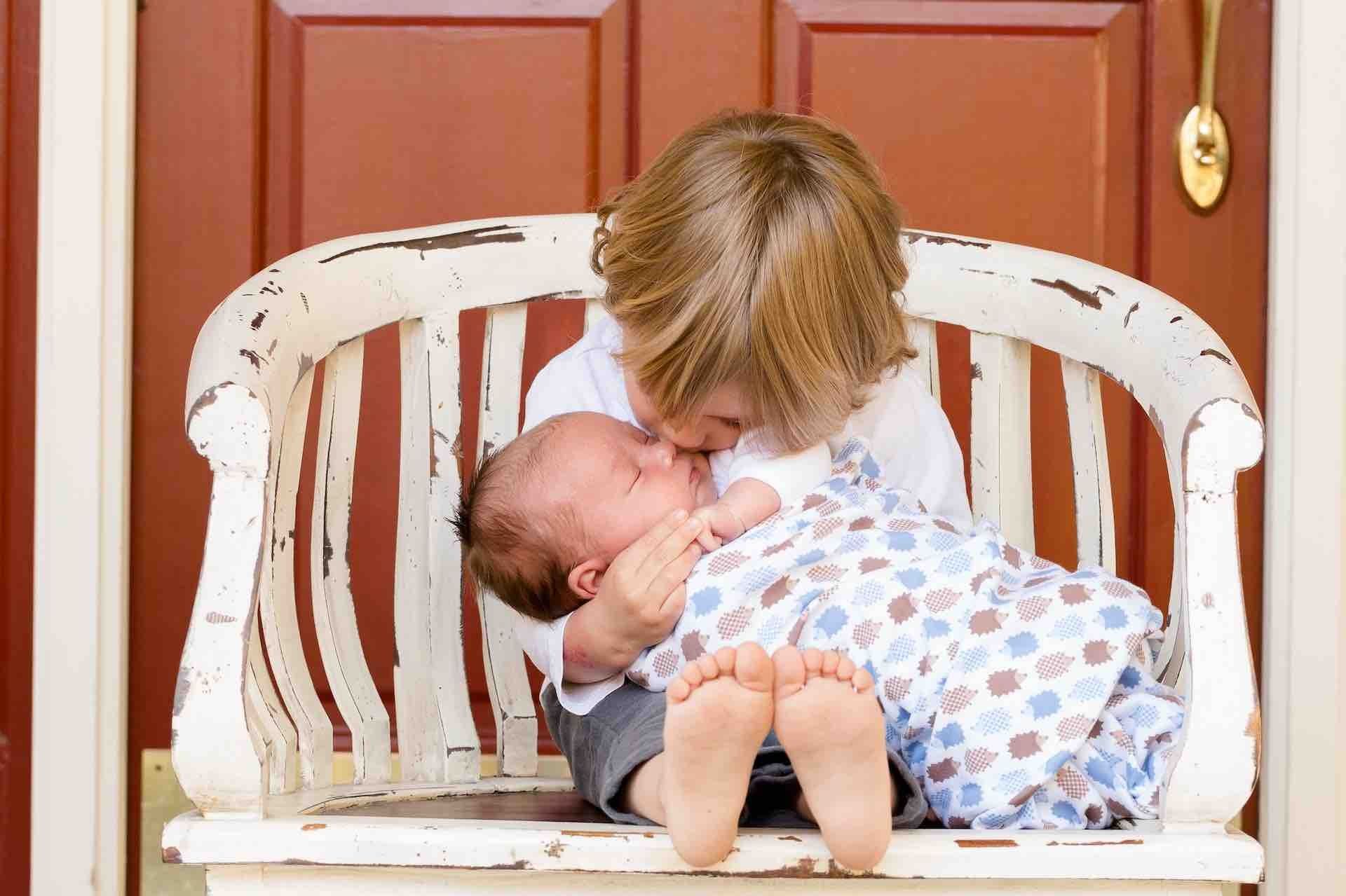 Niño sostiene a un bebé recién nacido