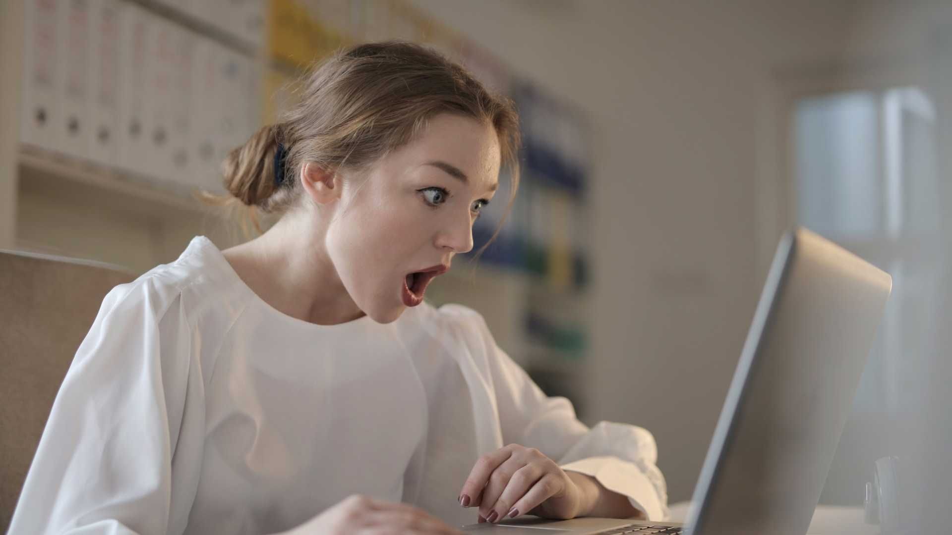 Mujer mira impresionada la pantalla de su computadora