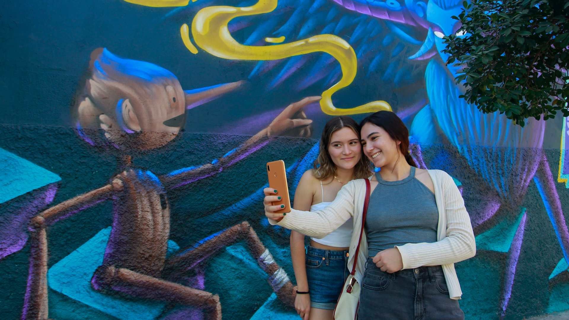 Dos mujeres se toman una foto junto a un mural inspirado en la película "Pinocchio" del cineasta mexicano Guillermo del Toro