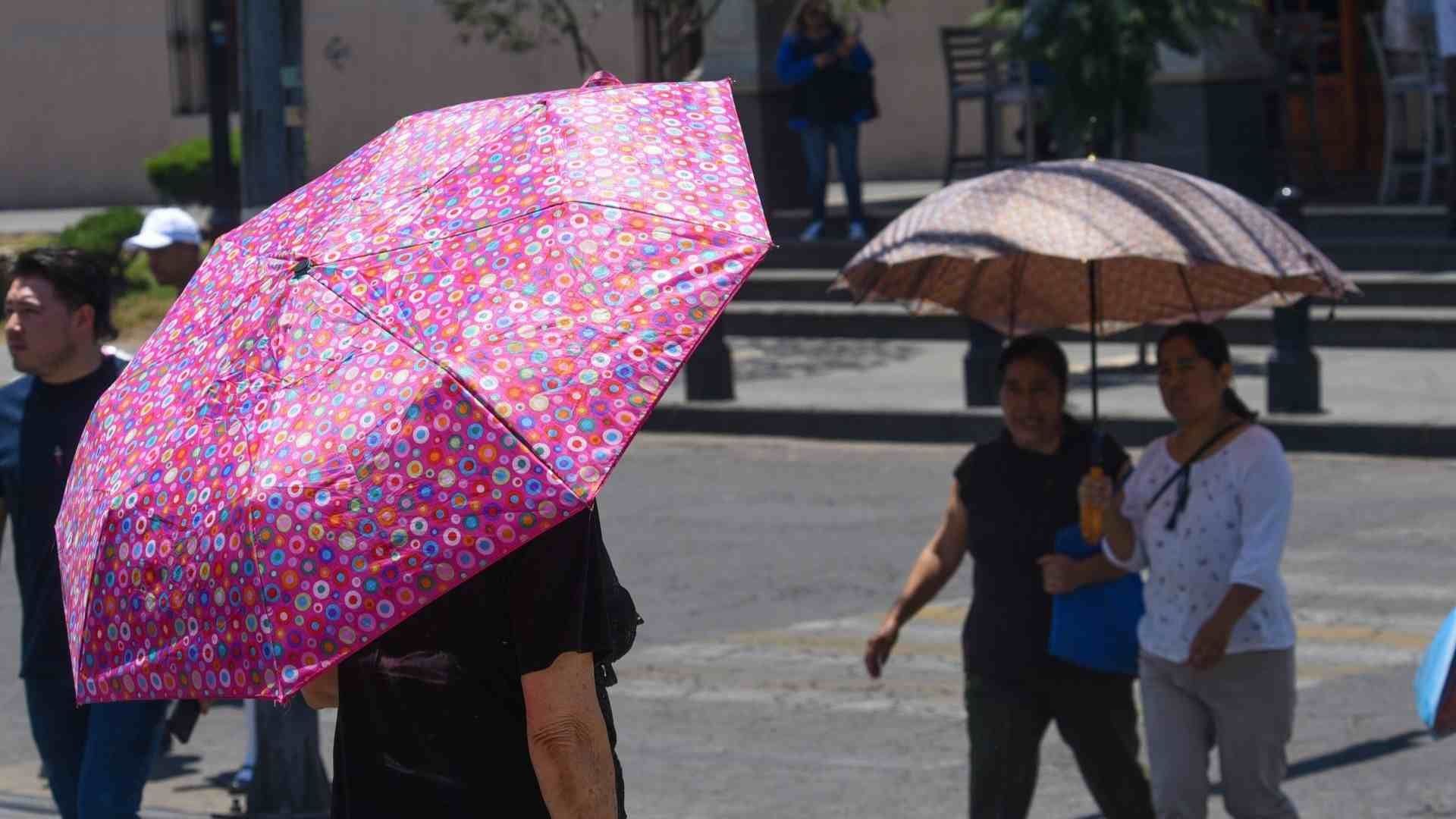 Personas usan sombrillas por ola de calor