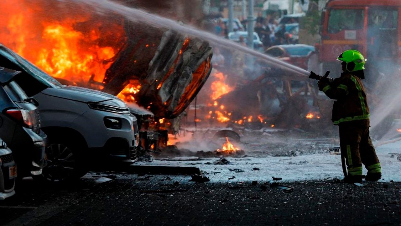 Bombero sofocando fuego en autos estacionados.