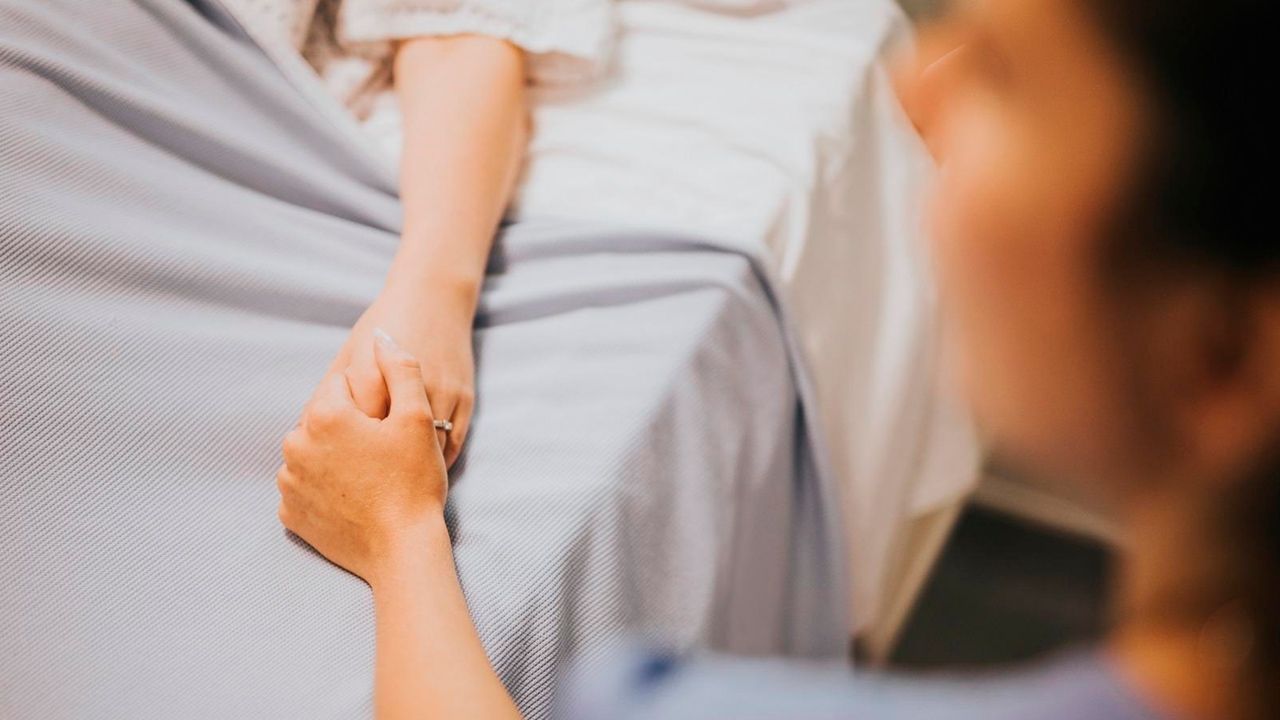 Una cuidadora sosteniendo la mano de un paciente, reflejando la compasión y confianza de las cuidadoras. 