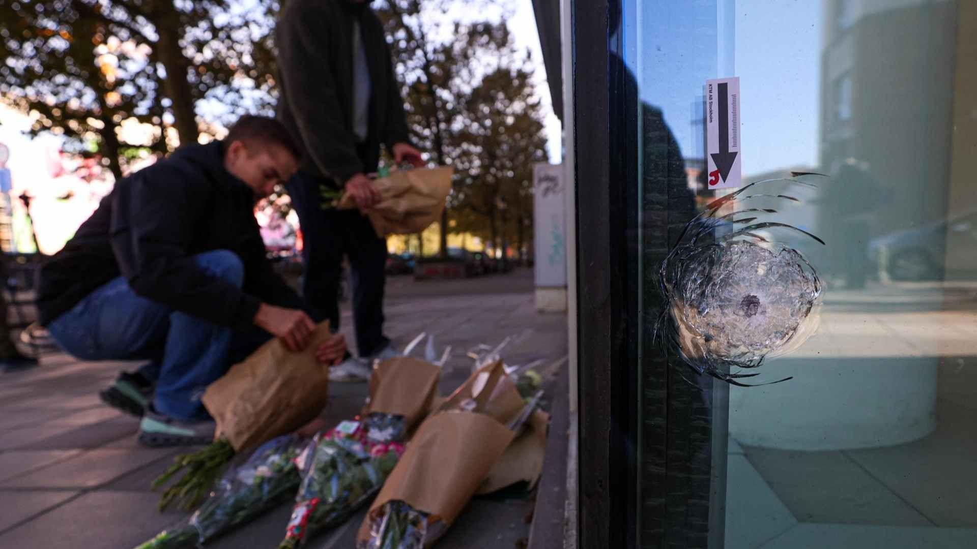 Personas colocaron flores junto a la sucursal bancaria donde aficionados de la selección de Suecia fueron ejecutados en Bruselas. Foto: EFE