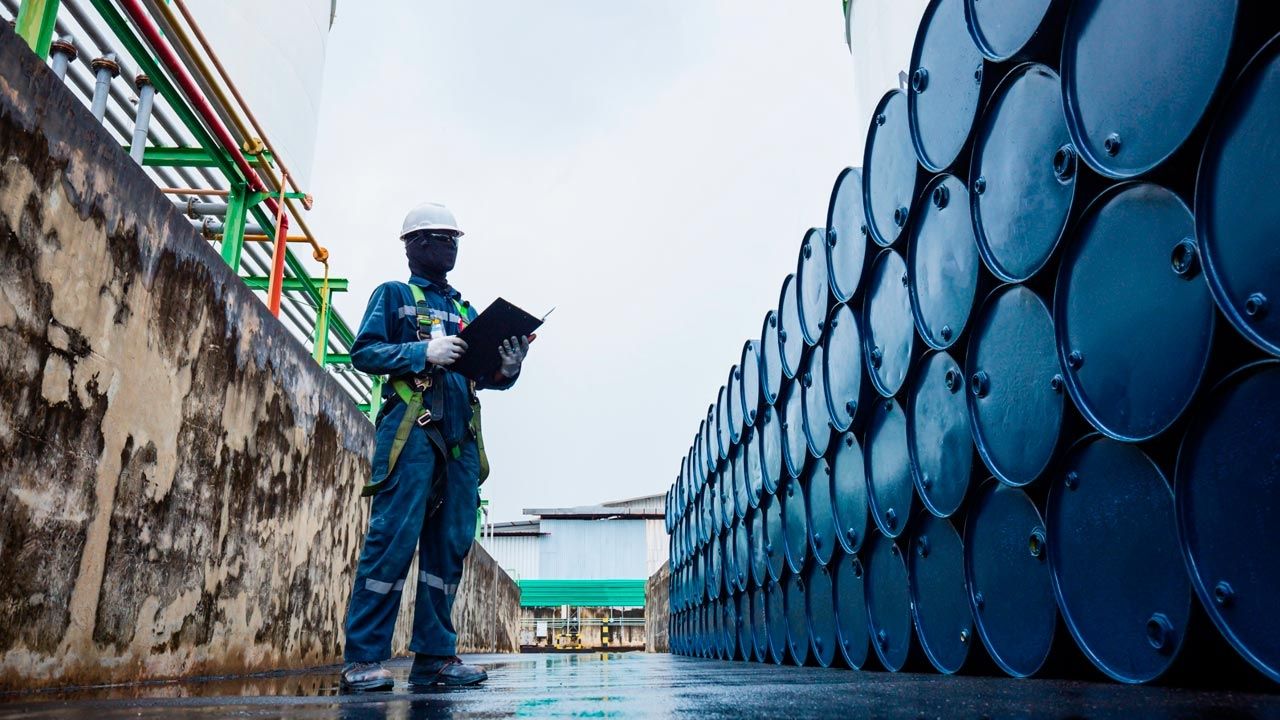 Trabajador inspeccionando barriles de petróleo