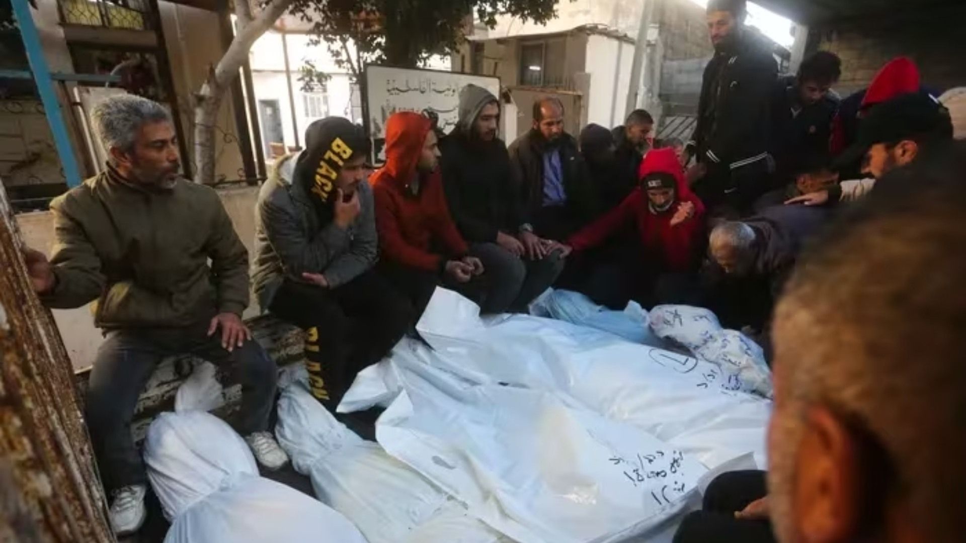 Palestinos se sientan junto a los cuerpos de familiares muertos en la Guerra contra Israel