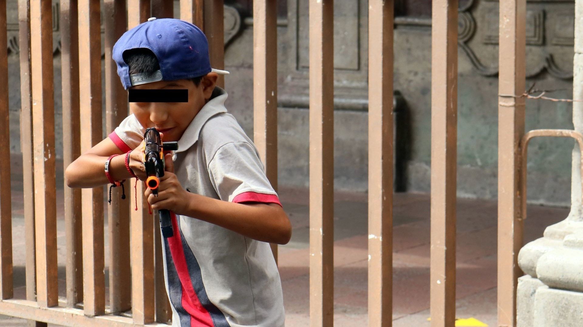 Niño le apunta a fotógrafo con una pistola de plástico. 