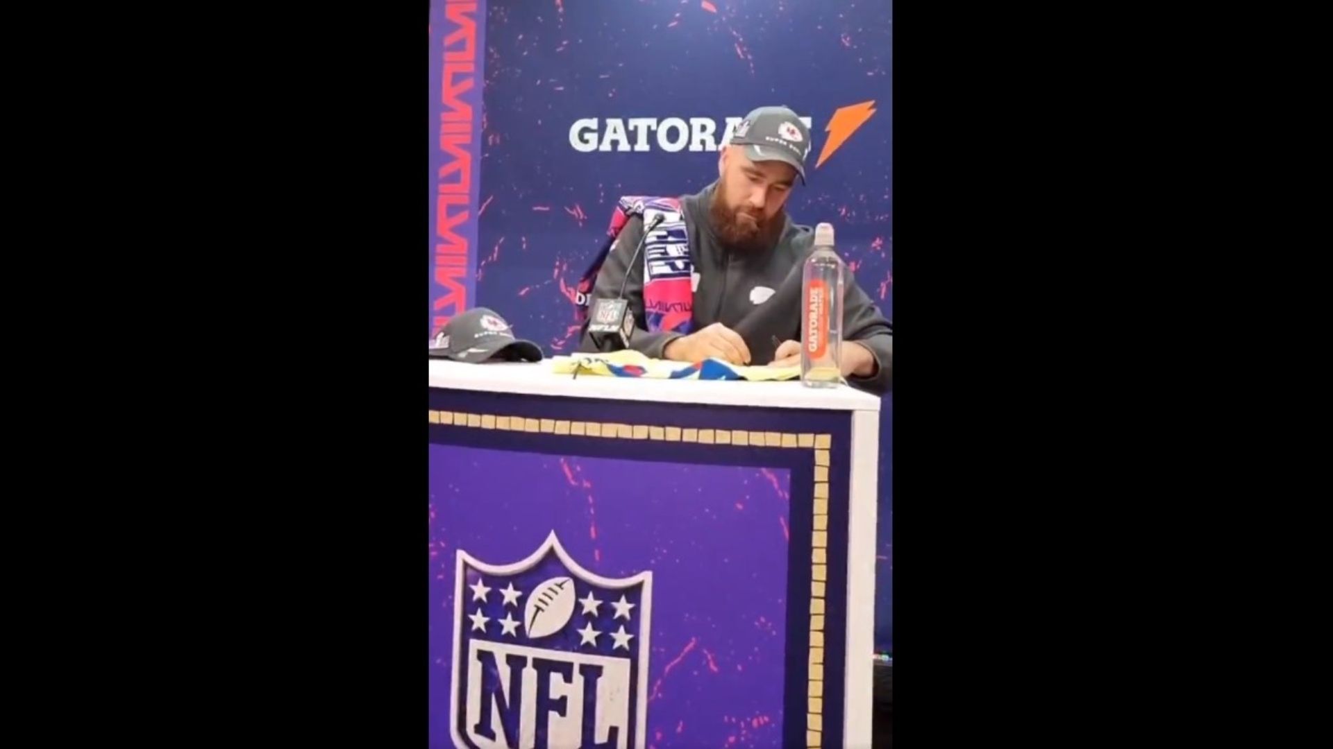 El momento en que Travis Kelce estampa su firma en un jersey del América. Foto: TUDN