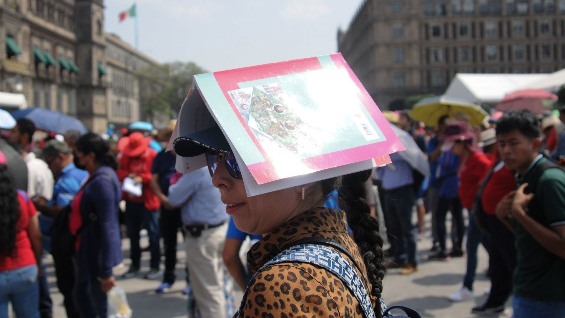 Una mujer utiliza un libro para protegerse del sol en la Ciudad de México, 15 de abril de 2024